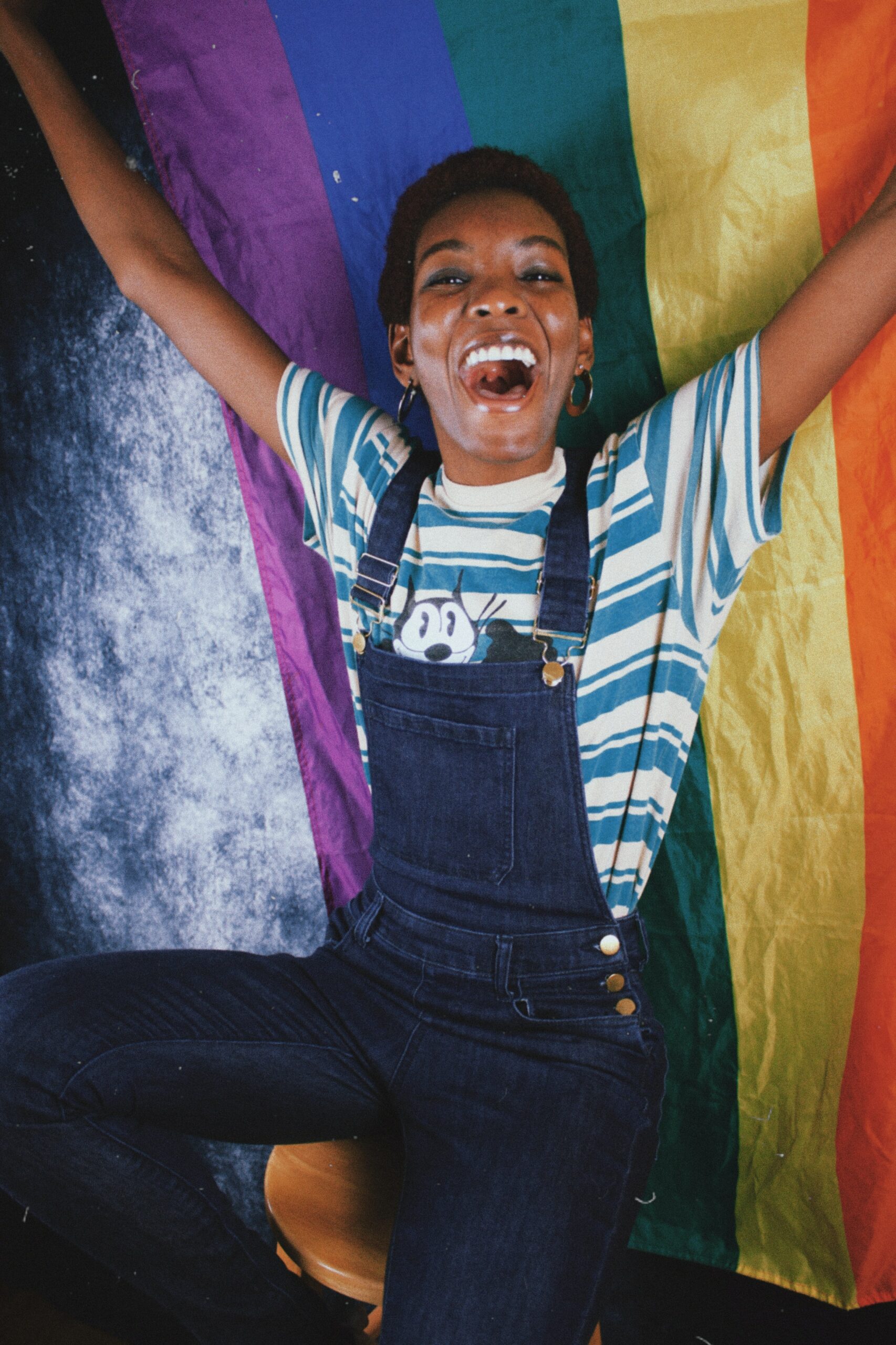 A smiling woman holding a rainbow pride flag